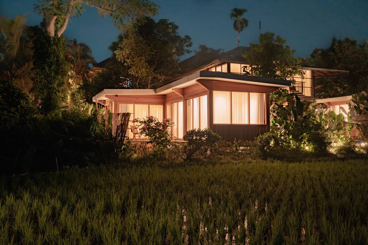 A modern house with large windows and a well-lit exterior at dusk.