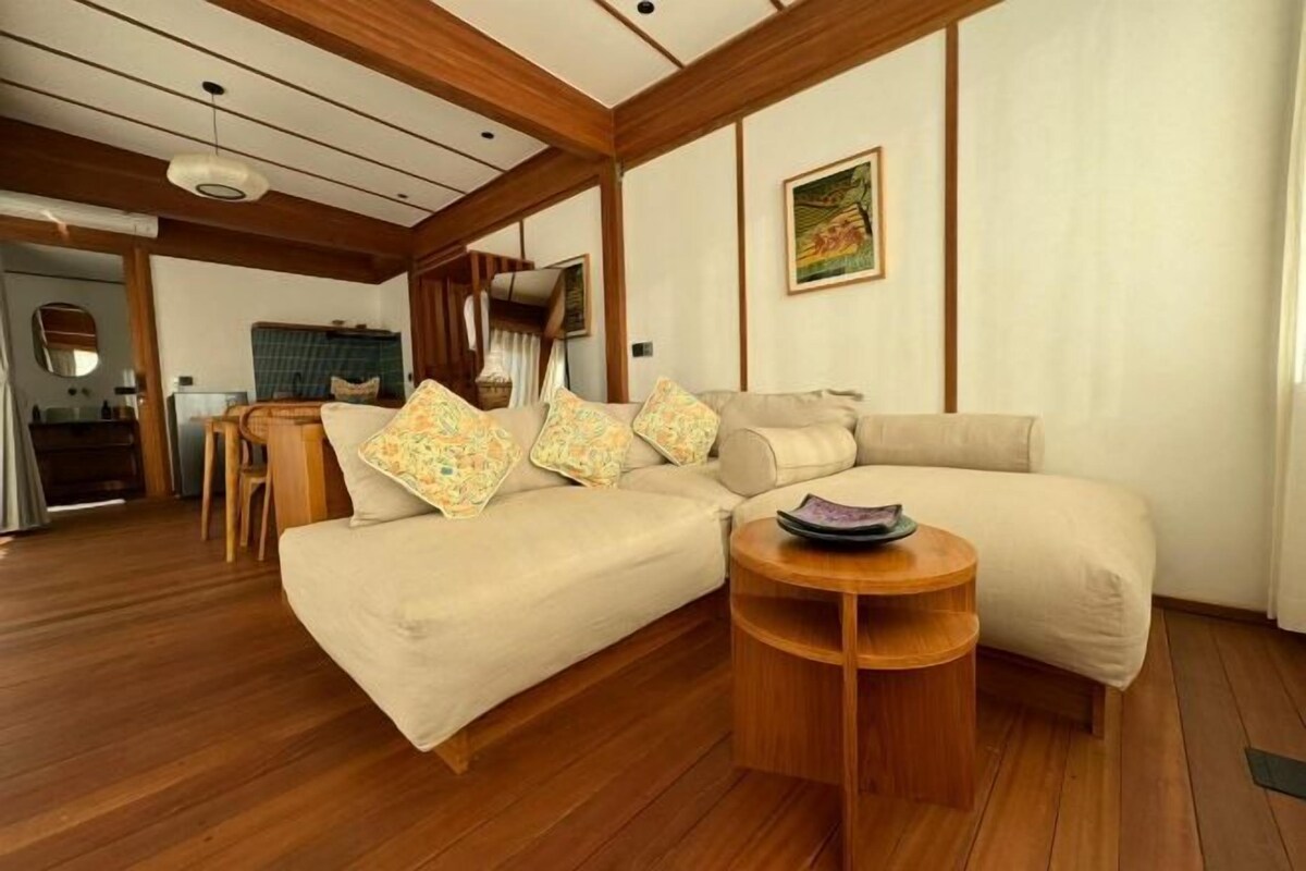 A cozy living room with a sofa, a round wooden coffee table, and a painting on the wall.
