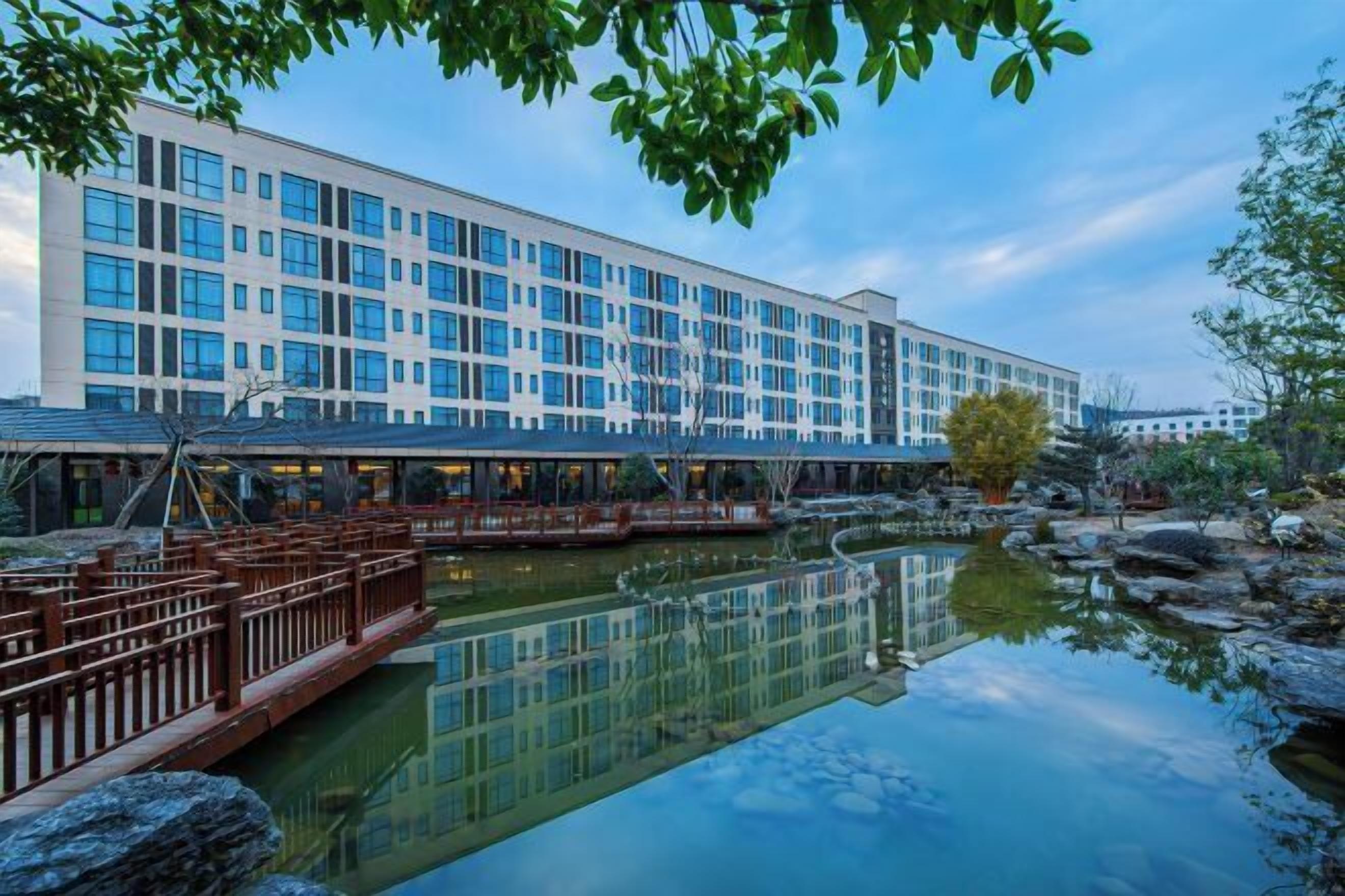 Ein modernes Hotel mit einem spiegelnden Pool, einer Holzdarlegung und Blick auf die Fassade des Gebäudes.