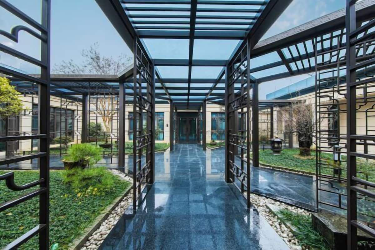 A covered walkway with glass panels and metal railings, leading to a building entrance.
