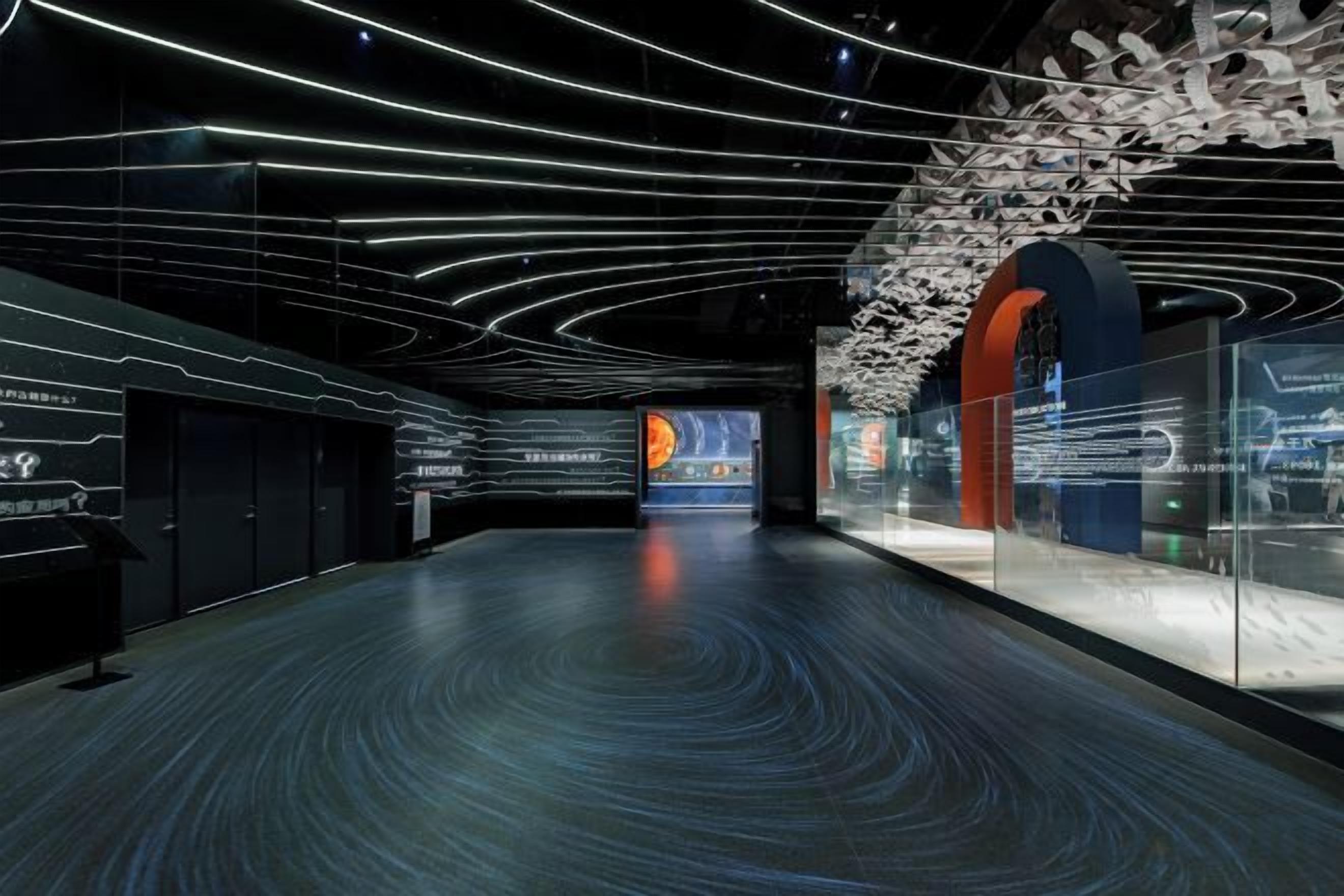 A modern interior with curved ceiling lines, a central display, and a glass wall with text.