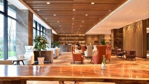 A spacious lobby with a wooden reception desk, seating area, and large windows. - Heye Hotel (Anji)