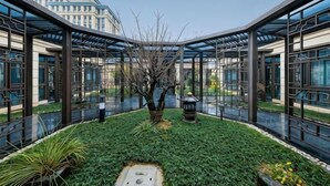 A courtyard with a central tree, glass walls, and a metal roof structure. - Heye Hotel (Anji)