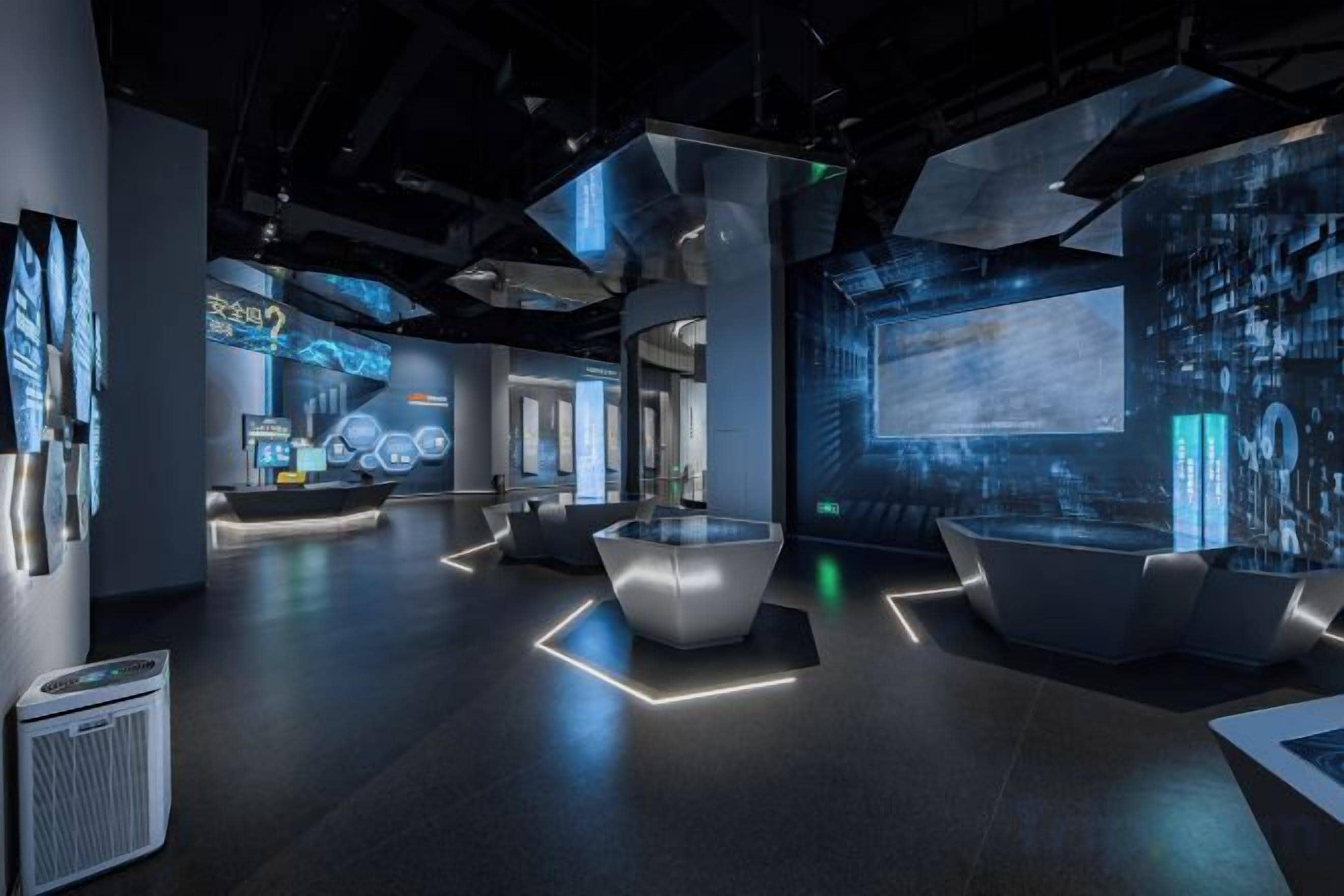 A modern interior with a central seating area, a large screen, and digital displays.