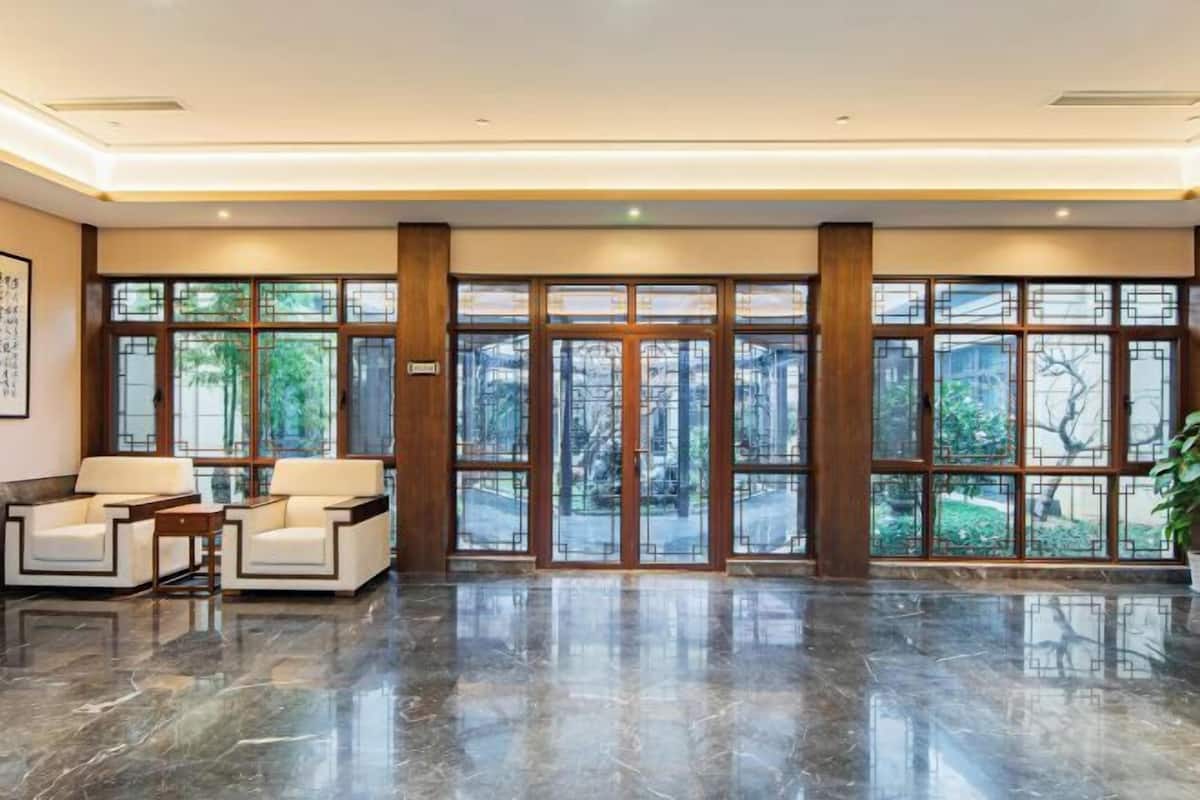 A lobby with a marble floor, two sofas, and large windows with a view of greenery.