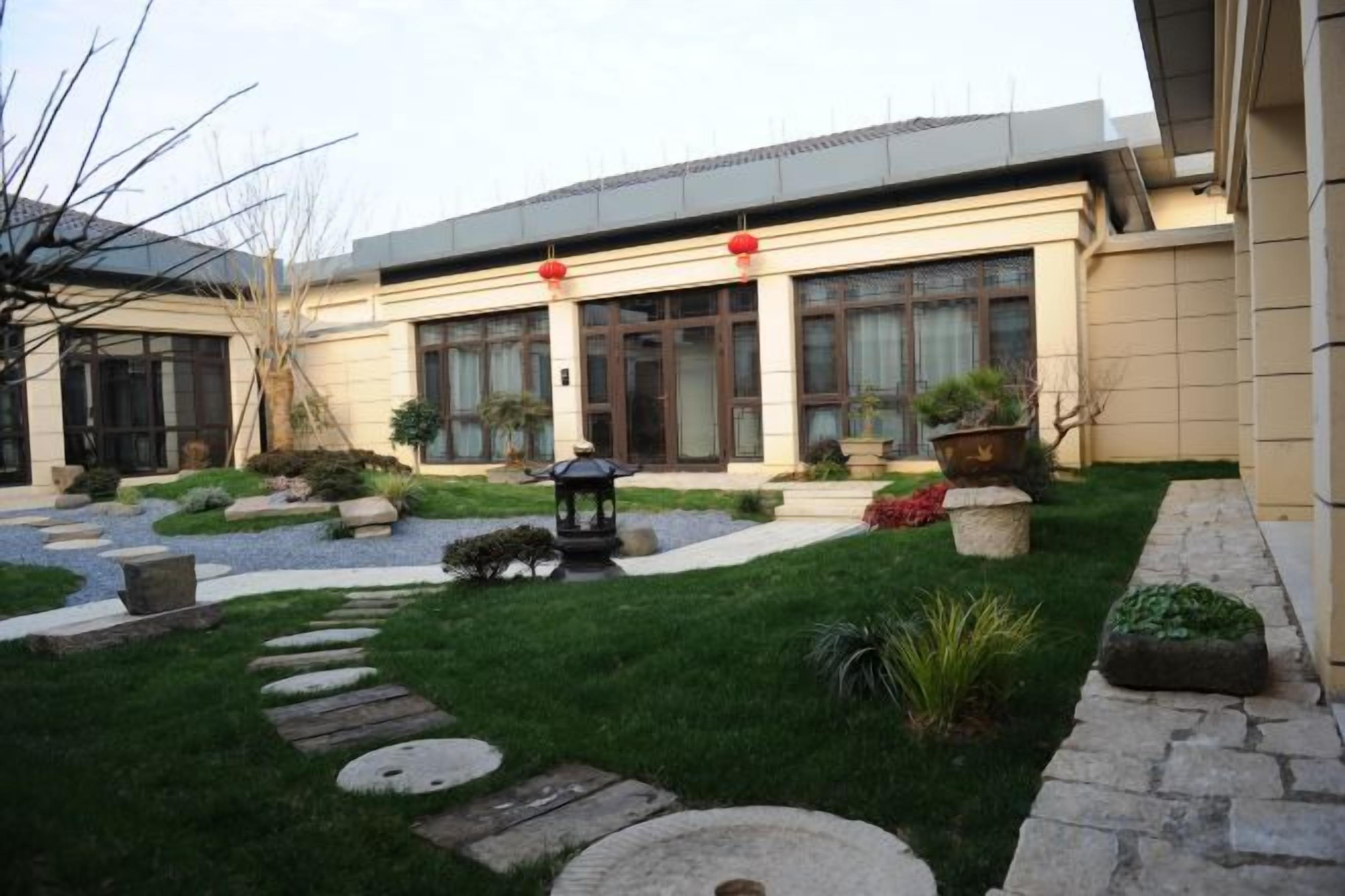 Un edificio con un patio empedrado, escalones de piedra y plantas en macetas.