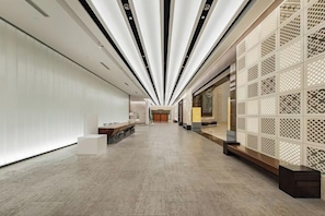 Un intérieur moderne avec un long couloir, un comptoir d’accueil et un élément de séparation décoratif.