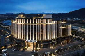 A multi-story hotel with a central courtyard, surrounded by parking and a road. - Heye Hotel (Anji)