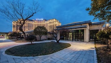 Un hotel con fachada moderna, un patio ajardinado y una entrada destacada.