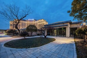 A hotel with a modern facade, a landscaped courtyard, and a prominent entrance. - Heye Hotel (Anji)