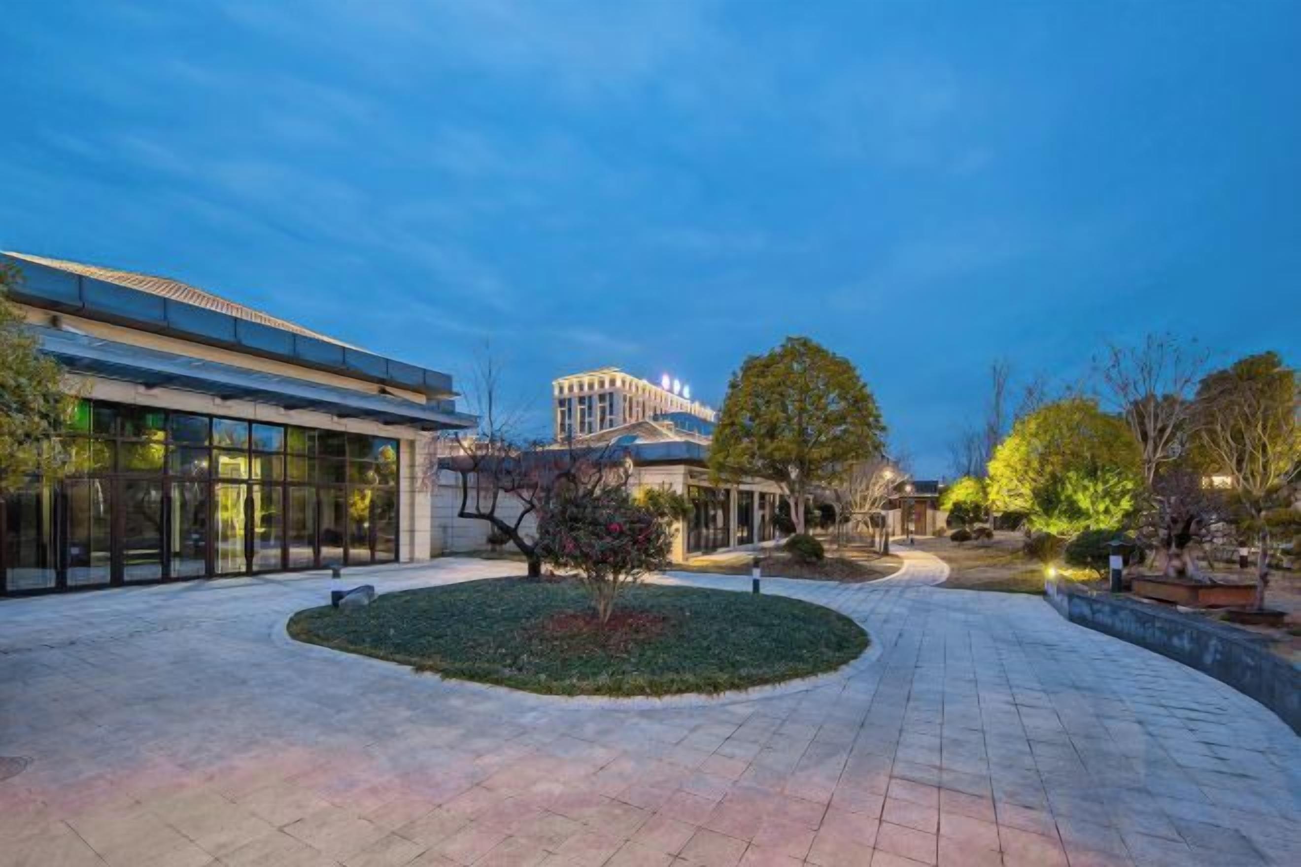 A courtyard with a building, trees, and a paved walkway.