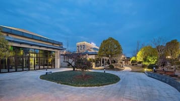 Une cour intérieure avec un bâtiment, des arbres et un chemin piétonnier dallé.