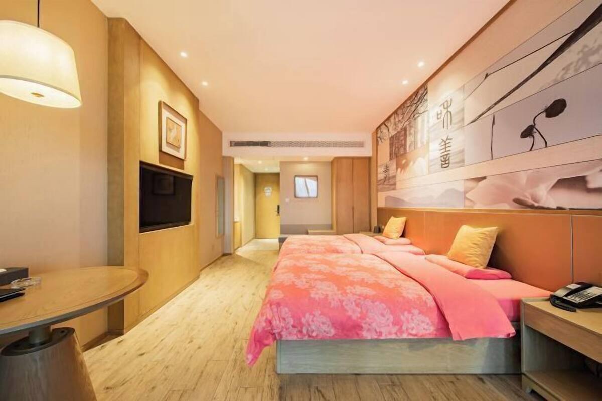 A modern hotel room with a large bed, a desk, and a television.