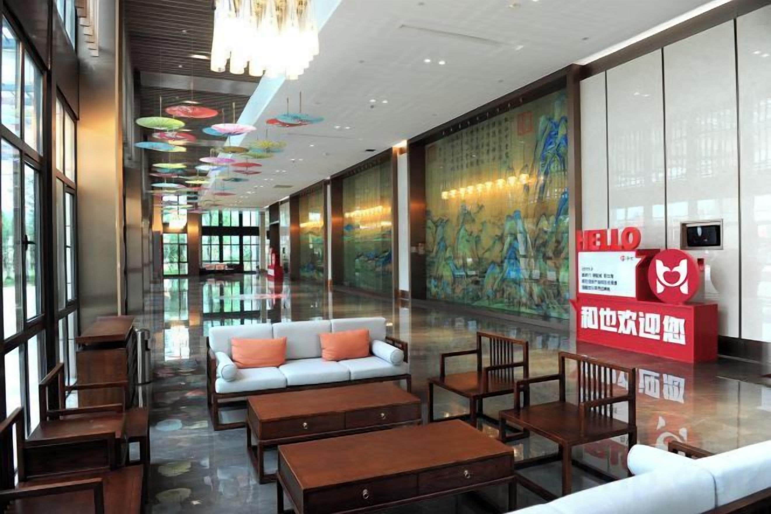 A hotel lobby with a sofa, tables, and a large mural.