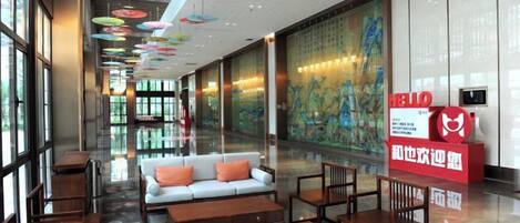 A hotel lobby with a sofa, tables, and a large mural.