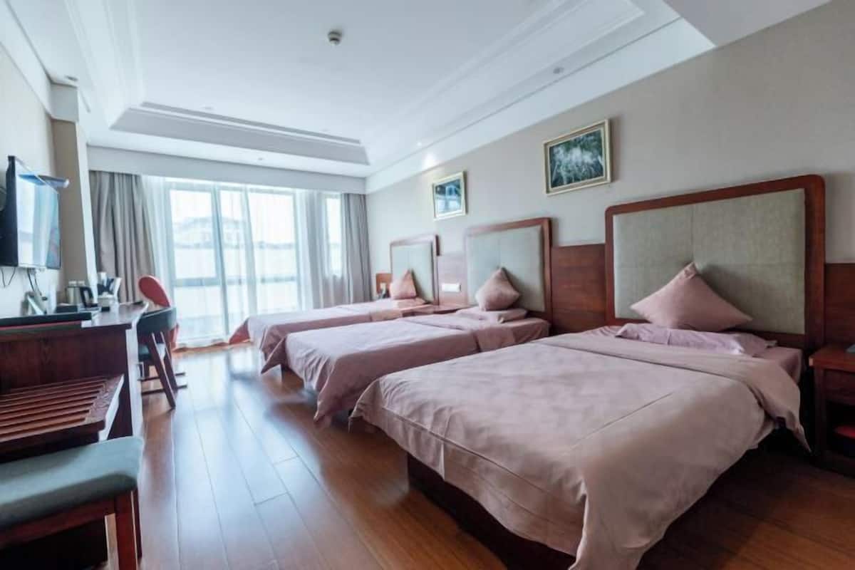 A hotel room with two beds, a desk, a chair, and a television.