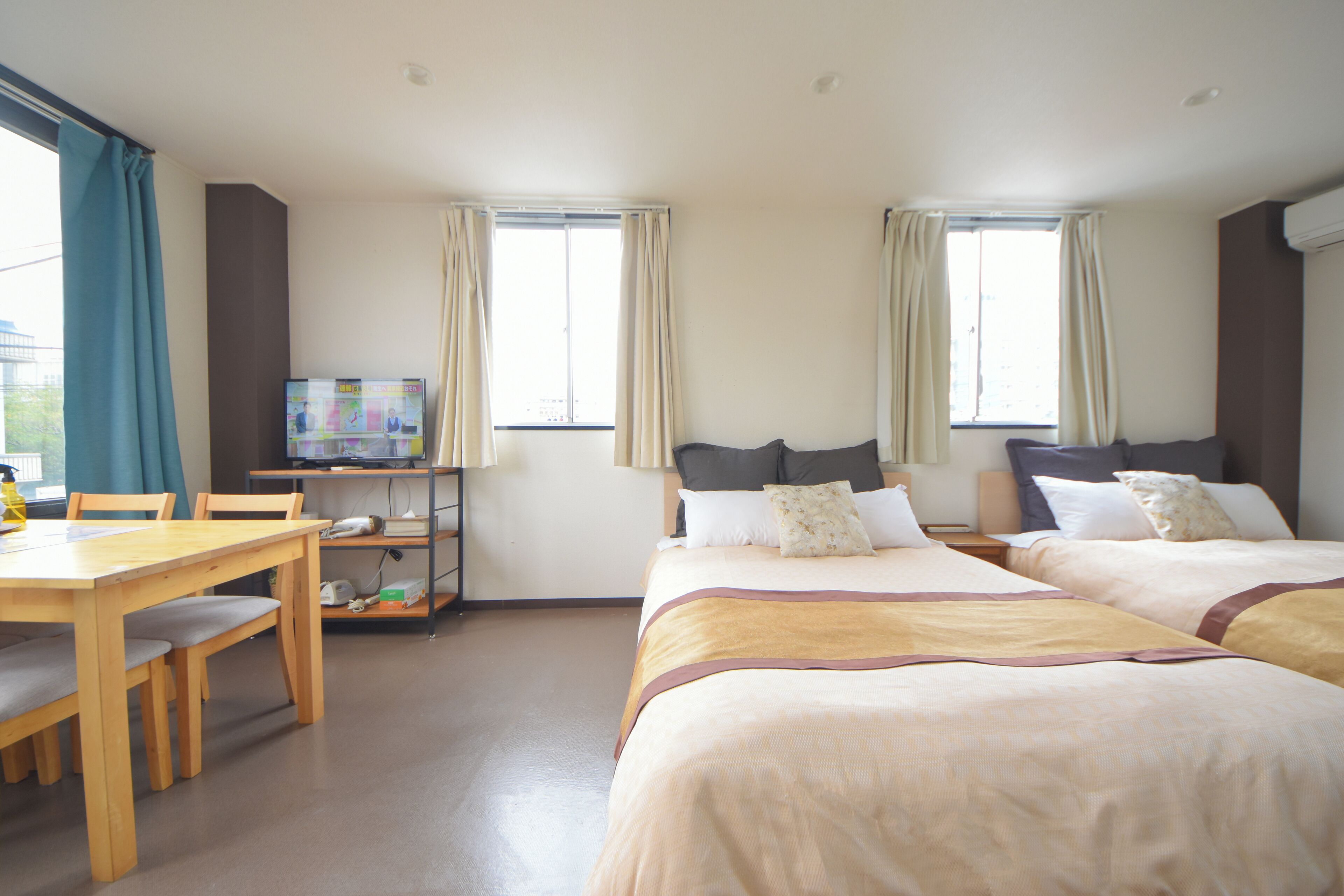 A hotel room with two beds, a desk, and a television.
