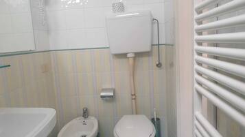 A bathroom with a bidet, toilet, and a bathtub.