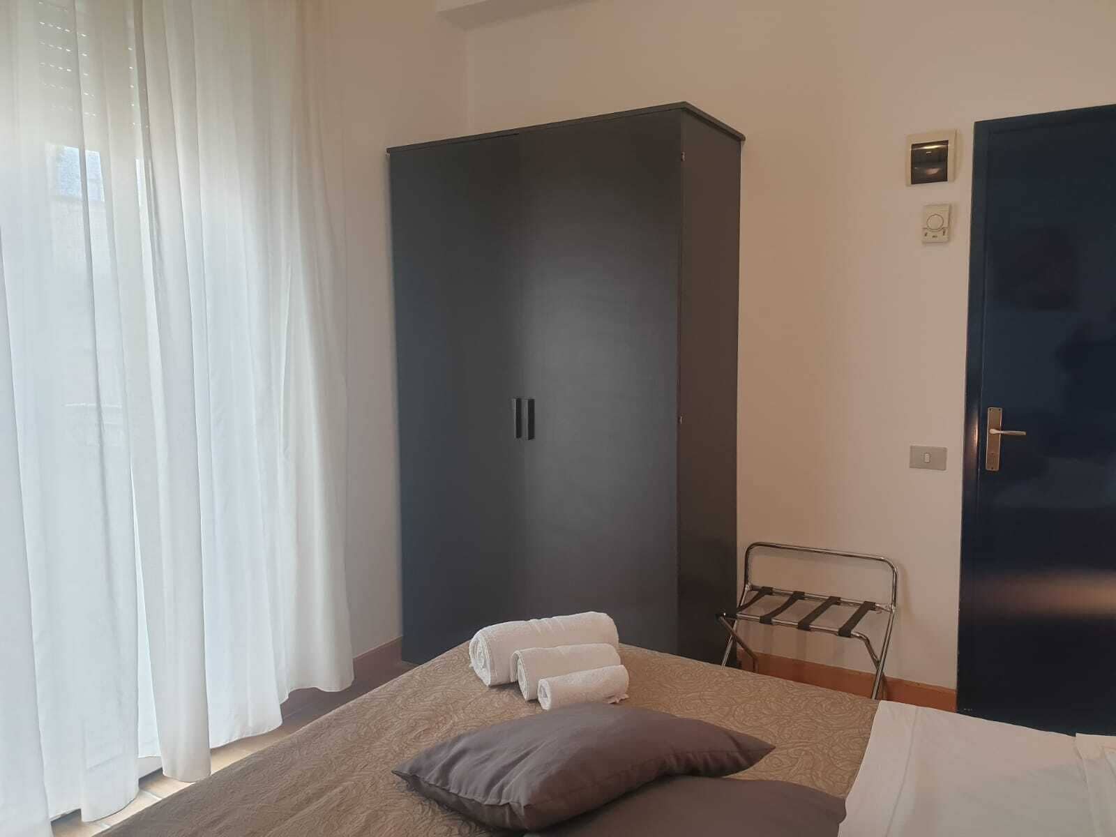 A bedroom with a bed, a wardrobe, a door, and a towel rack.