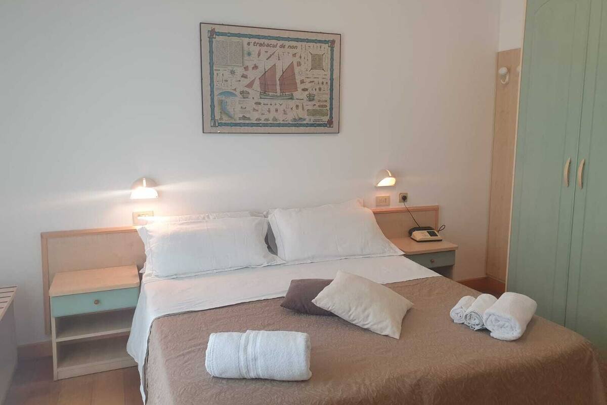 Ein Schlafzimmer mit einem Bett, zwei Nachttischen, einem Schrank und einer Wandkarte.