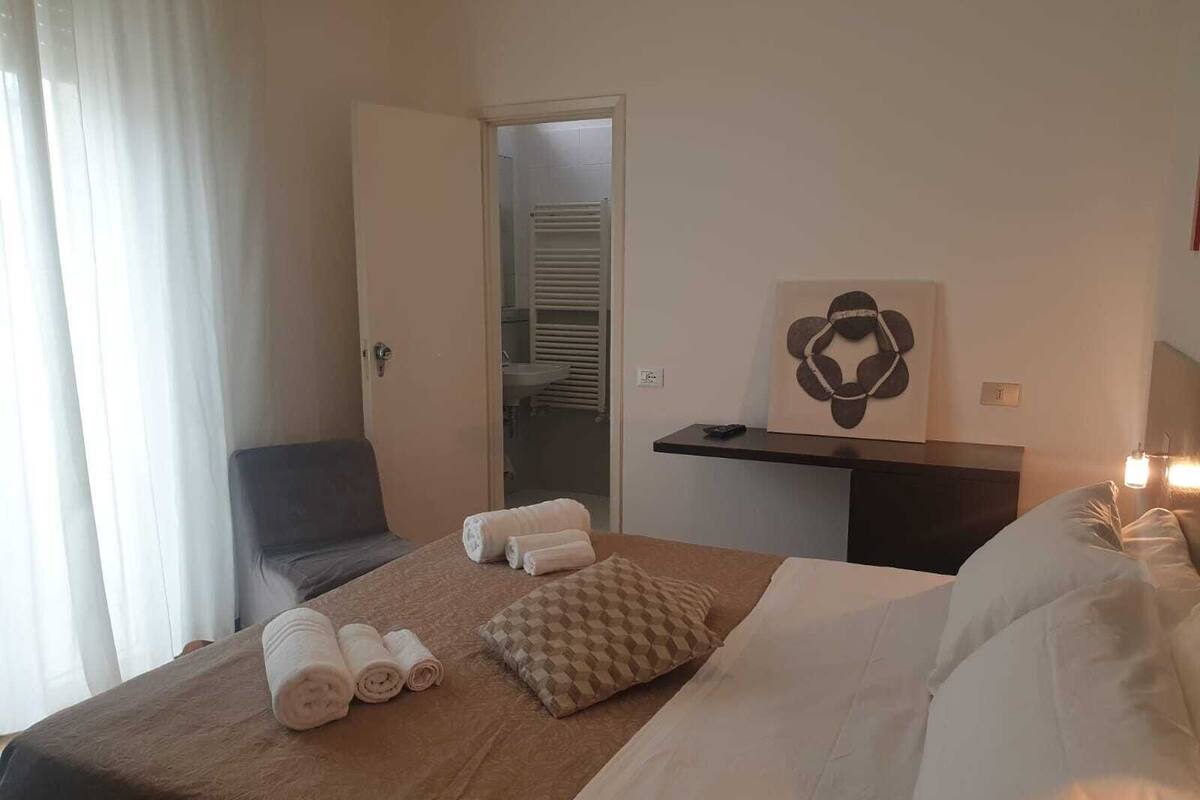 Ein Hotelzimmer mit Bett, Schreibtisch, Stuhl und einem durch eine offene Tür einsehbaren Badezimmer.