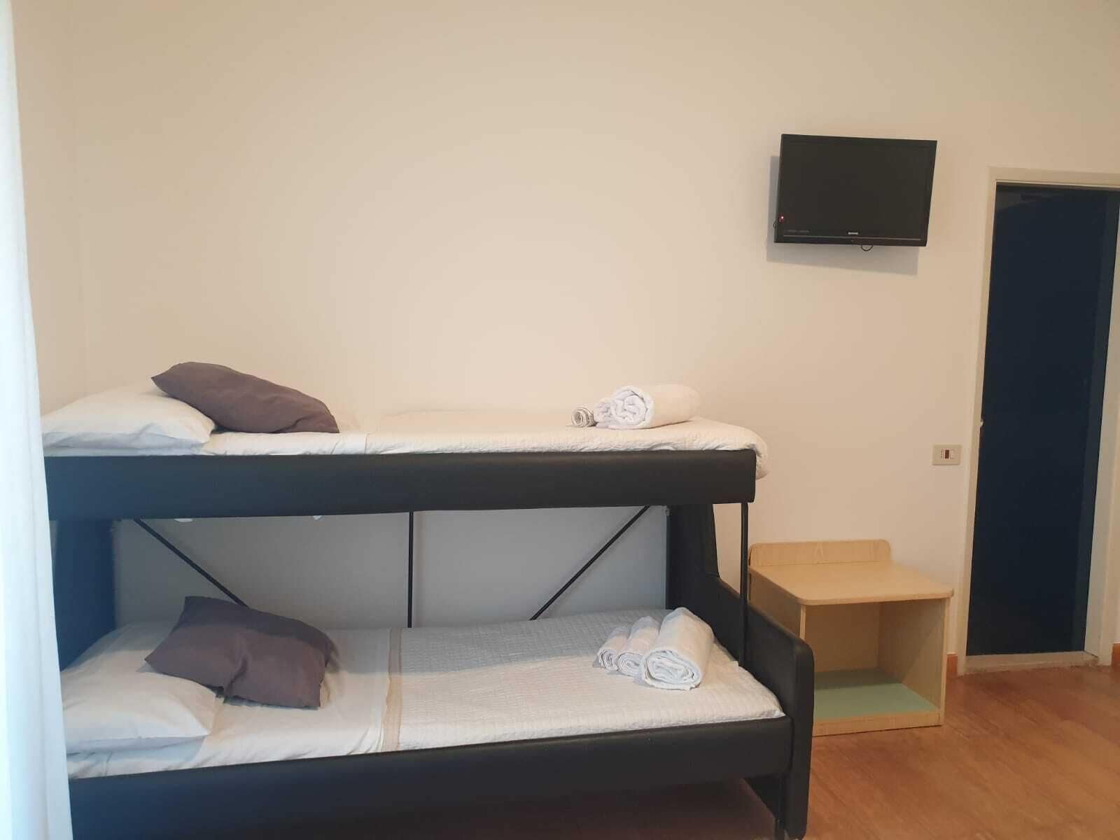 A bunk bed room with a television mounted on the wall and a door to the right.