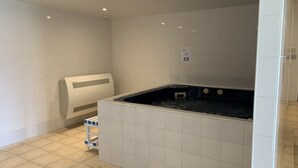 Une salle de bain moderne avec une grande baignoire, des murs recouverts de carreaux blancs et un sol carrelé.