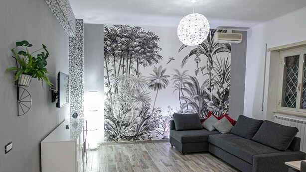 A modern living room with a grey sofa, a small table, and a decorative plant. - Cozy and renovated ground floor apartment connected (Roma)