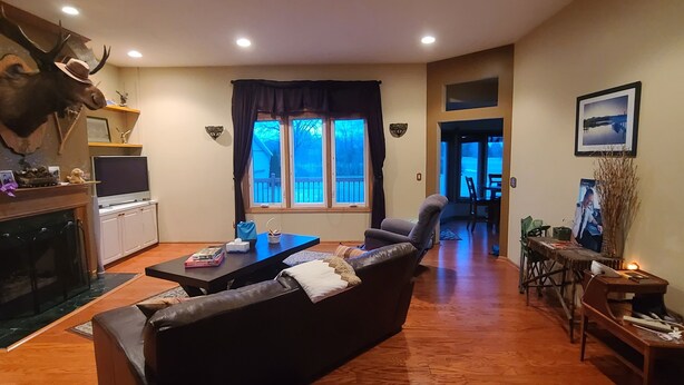 Ein Wohnzimmer mit Kamin, einer Couch, einem Fernseher und einem Essbereich mit Tisch und Stühlen.