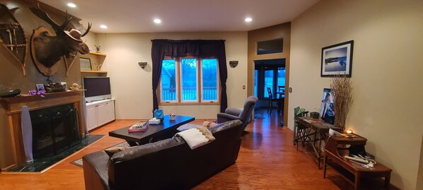 Una sala de estar con chimenea, un sofá, un televisor y un comedor con mesa y sillas.