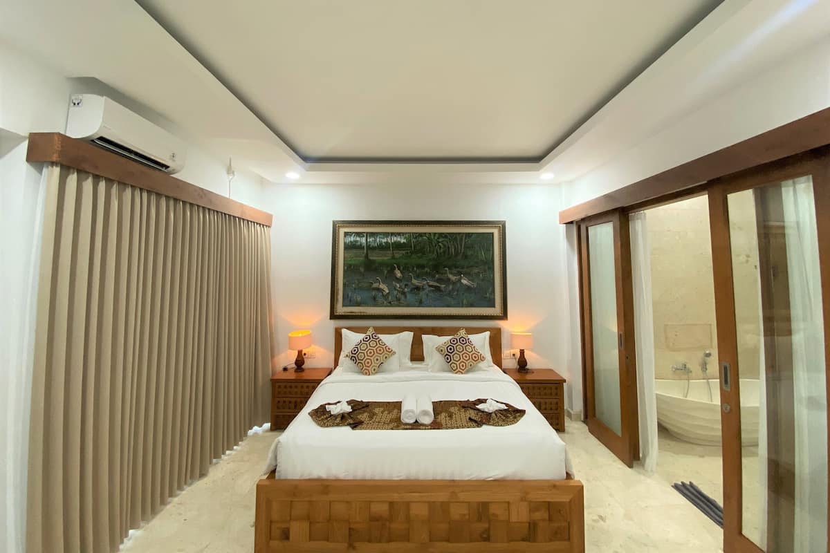 Ein Schlafzimmer mit Bett, einem Gemälde, einer Schiebetür und einem Deckenventilator.