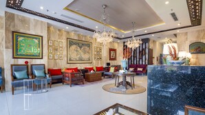 A spacious lobby with a high ceiling, chandeliers, a marble reception desk, and comfortable seating areas. - DB HOTEL (Nha Trang)