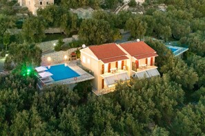 A two-story house with a red-tiled roof, a swimming pool, and a stone wall. - Villa Kalithea in Nisaki (Corfu)