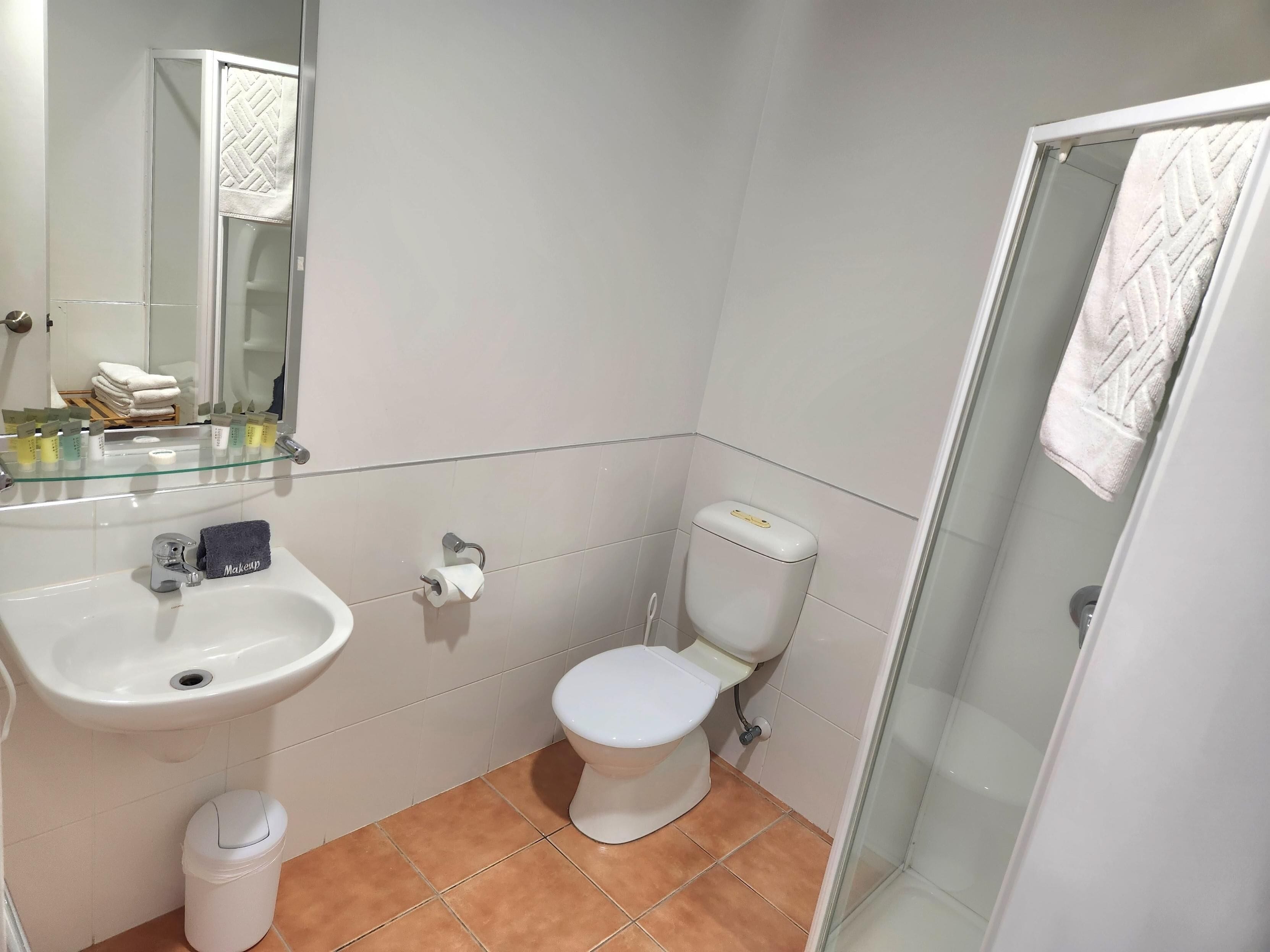 A bathroom with a sink, toilet, and glass shower enclosure.