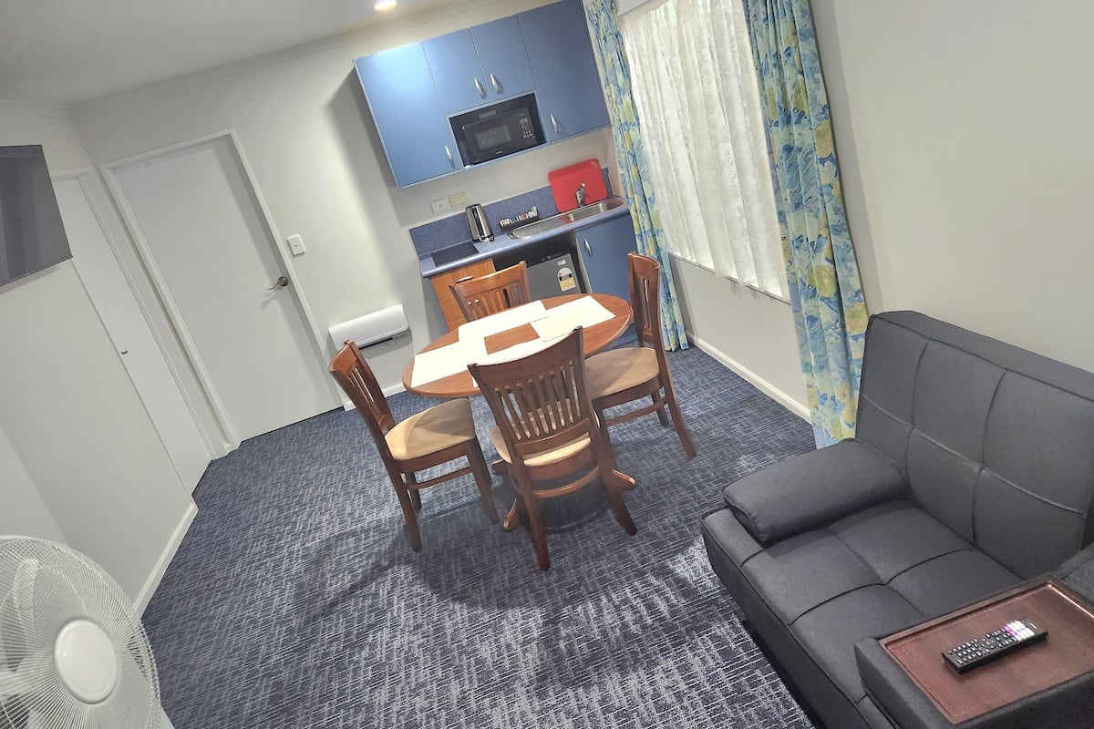 A compact living space with a dining area, kitchenette, and a sofa.