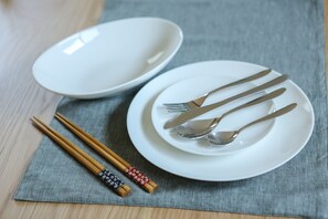 Una mesa para comer con palillos, un plato blanco y un bol sobre un mantel gris.