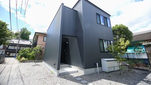 En modern byggnad i två våningar med en unik, kantig design, en liten trädgårdsyta och ett väl synligt utomhusområde.