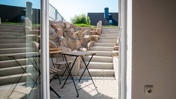 Blick auf eine Steintreppe, die zu einer Terrasse mit Tisch und Stühlen führt.