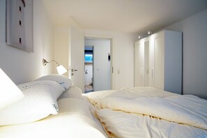 Une chambre à coucher comprenant un lit, une armoire et une porte donnant sur une autre pièce.
