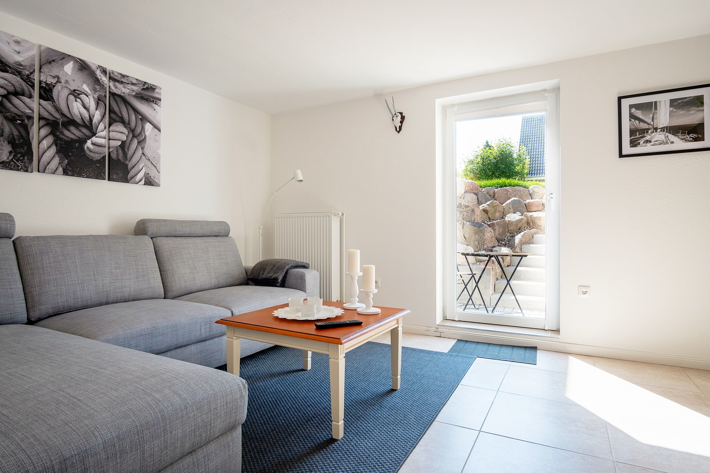Ein modernes Wohnzimmer mit einem grauen Sofa, einem Holztisch und einem blauen Teppich.