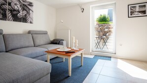 Un salon moderne avec un canapé gris, une table basse en bois et un tapis bleu.