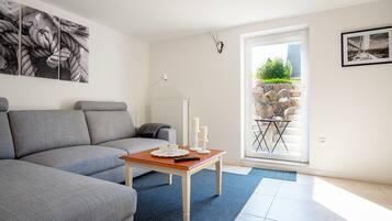 Ein modernes Wohnzimmer mit einem grauen Sofa, einem Holztisch und einem blauen Teppich.