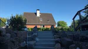 Une maison avec un toit en pente, une cheminée et un escalier en pierre menant à une porte.