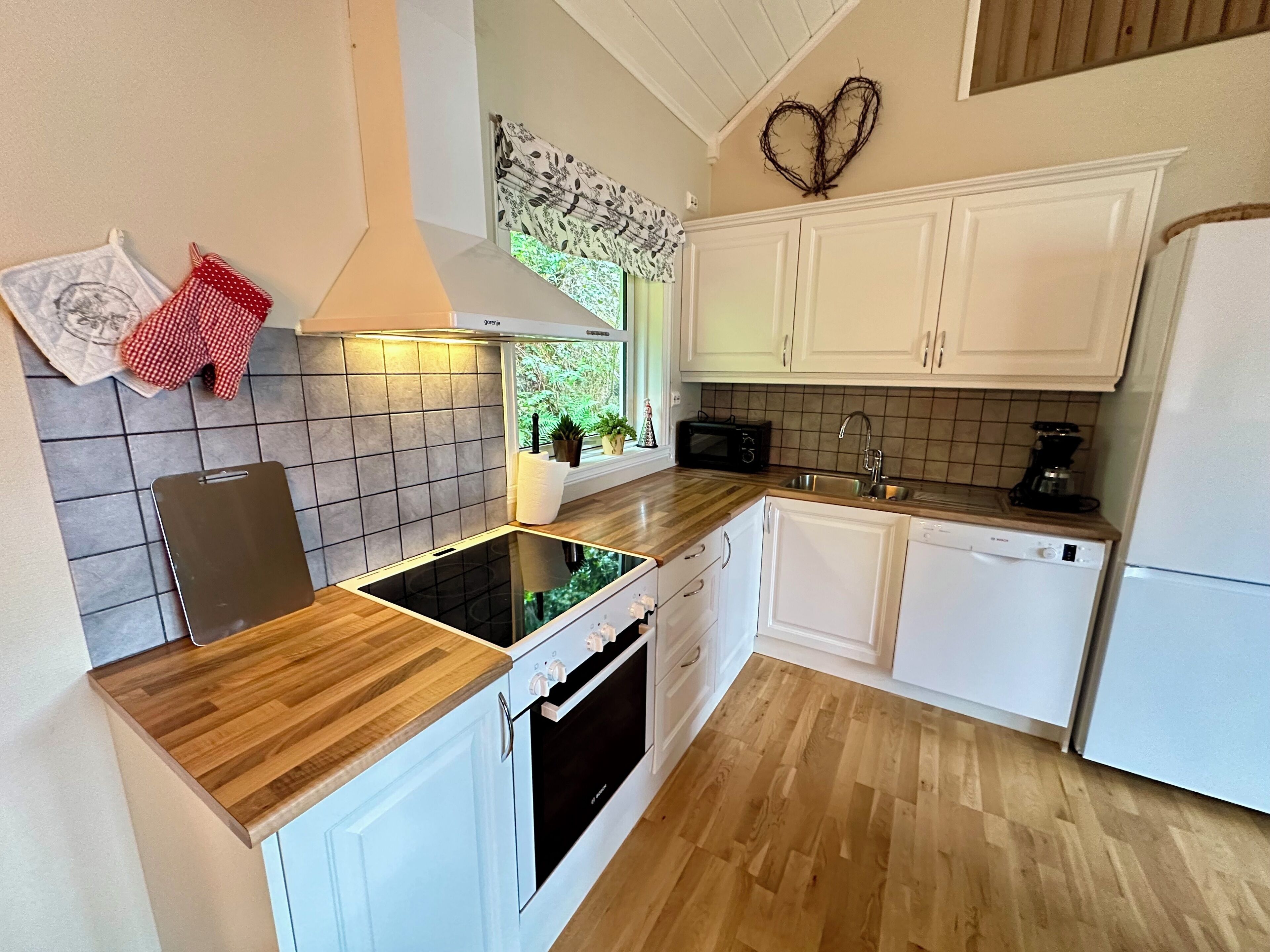 A modern kitchen with white cabinets, a wooden countertop, a built-in oven, a microwave, and a dishwasher.