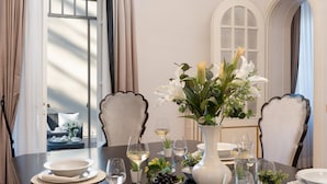 A dining table set with white plates, bowls, and glasses, surrounded by chairs with a scalloped edge design. A vase with white flowers is placed on the table. - Villa Irma 10 (Casciana Terme Lari)