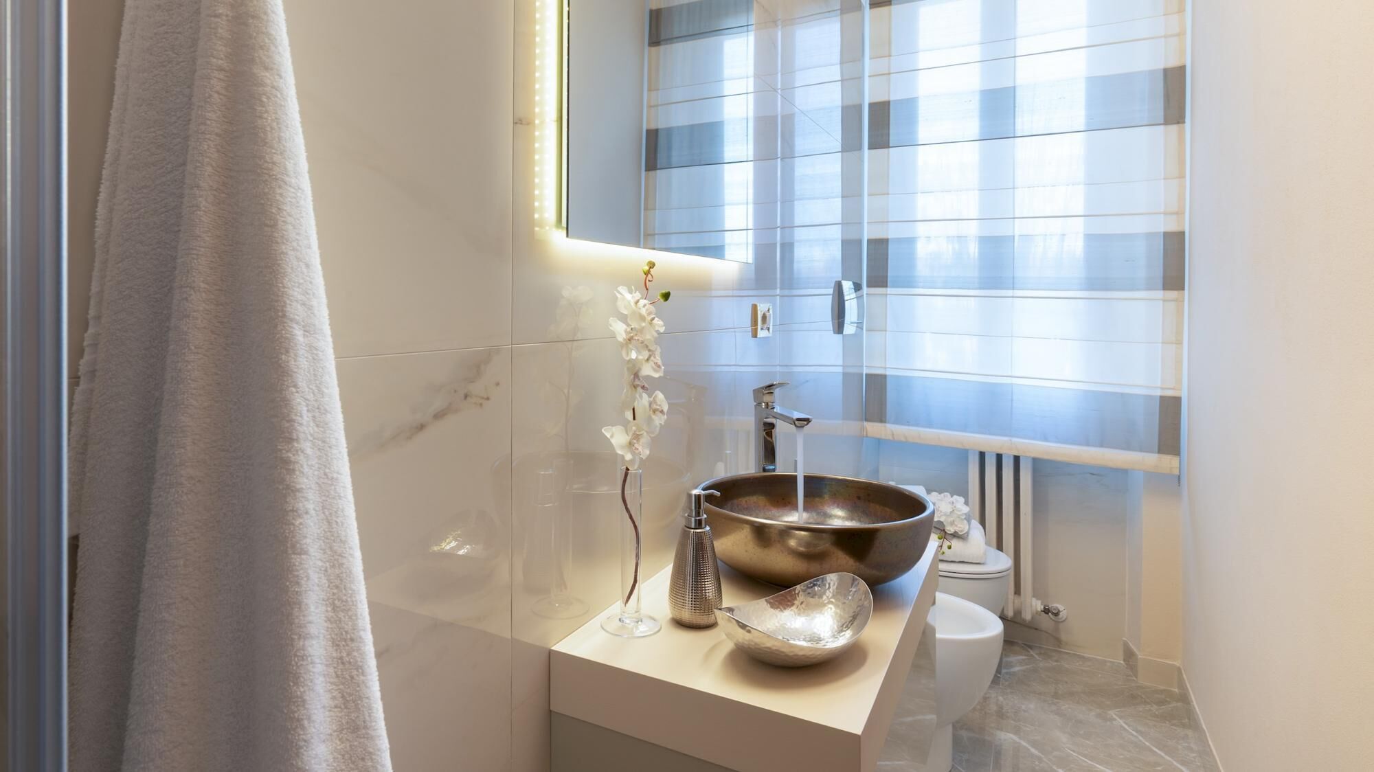 A modern bathroom with a large mirror, a vessel sink, and a toilet.