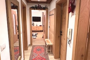 Un couloir avec des portes en bois, un banc, un tapis à motifs et un tapis en peau de vache sur le sol.