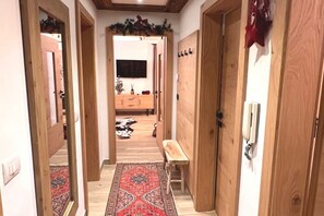 Un corridoio con porte in legno, una panca, un tappeto decorato e un tappeto in pelle di mucca sul pavimento.