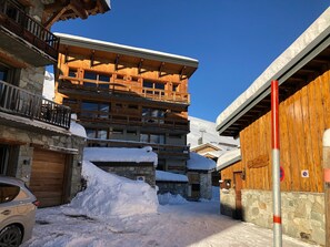 Guesthouse with a traditional alpine architectural style, featuring a stone entrance and multiple balconies.
