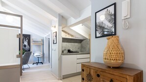 Een moderne keuken met een ingebouwde oven, een houten console tafel met een decoratieve vaas, en een lijstwerk kunstwerk aan de muur.